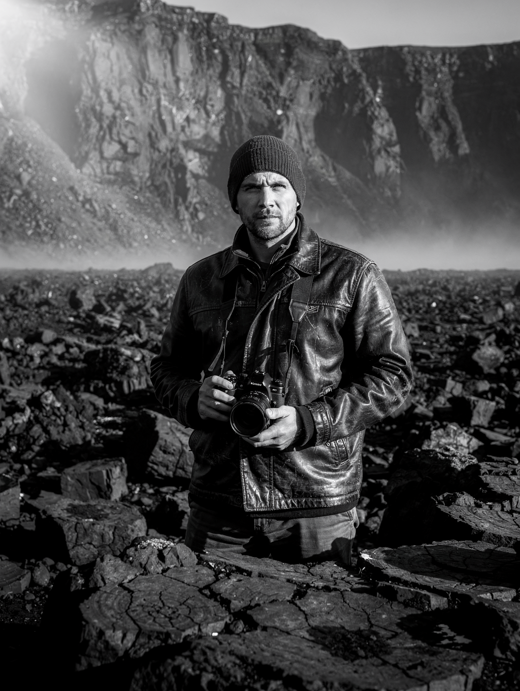 Landscape photographer reviewing medium-format field camera in remote sub-polar terrain